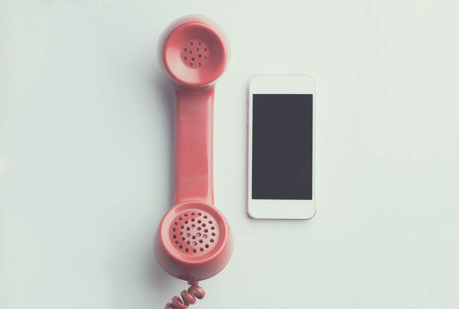 Artsy juxtaposition of white iPhone and pink (SALMON) rotary phone.