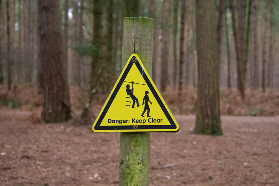 Danger sign keep clear in the forest where people ziplining kick/body check pedestrians.