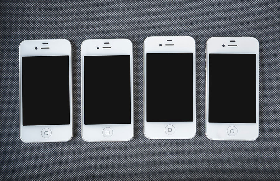 Four old white iPhones (maybe iPhone 5) side by side. I don't know if they were old when the picture was taken.