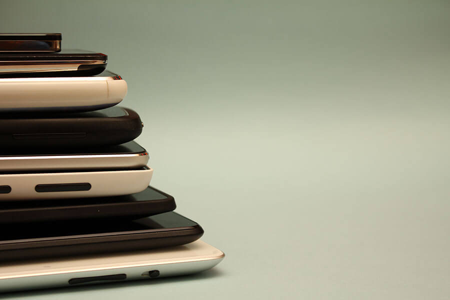 Pile of various smartphones neatly stacked.