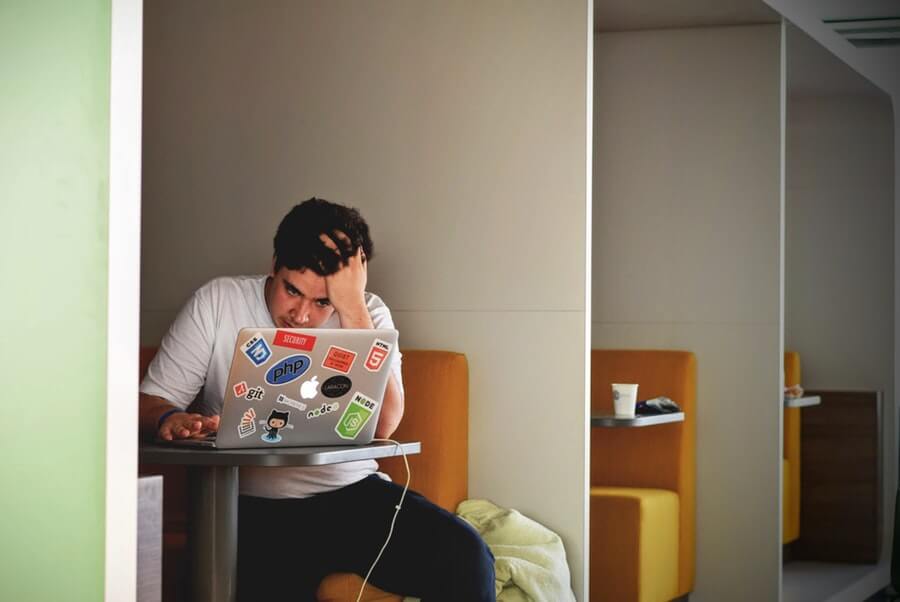 Man stressing out on laptop in cafe