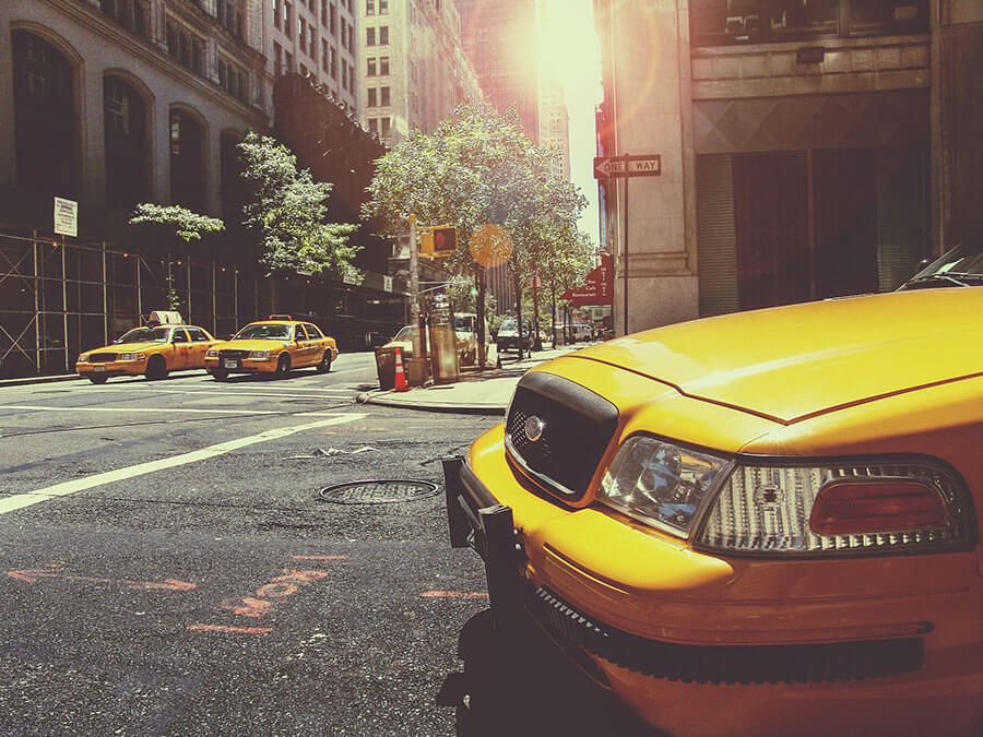 Three standard yellow american taxi cabs are having a secret meeting at an intersection.