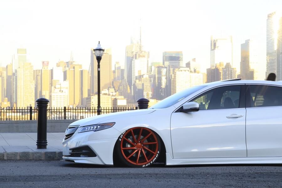 Custom lowered white Acura with body kit and orange rims.