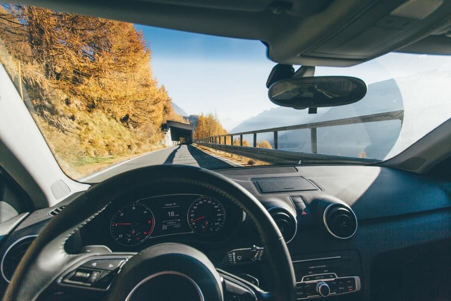 Driving an SUV in the daytime on a picturesque mountain road.