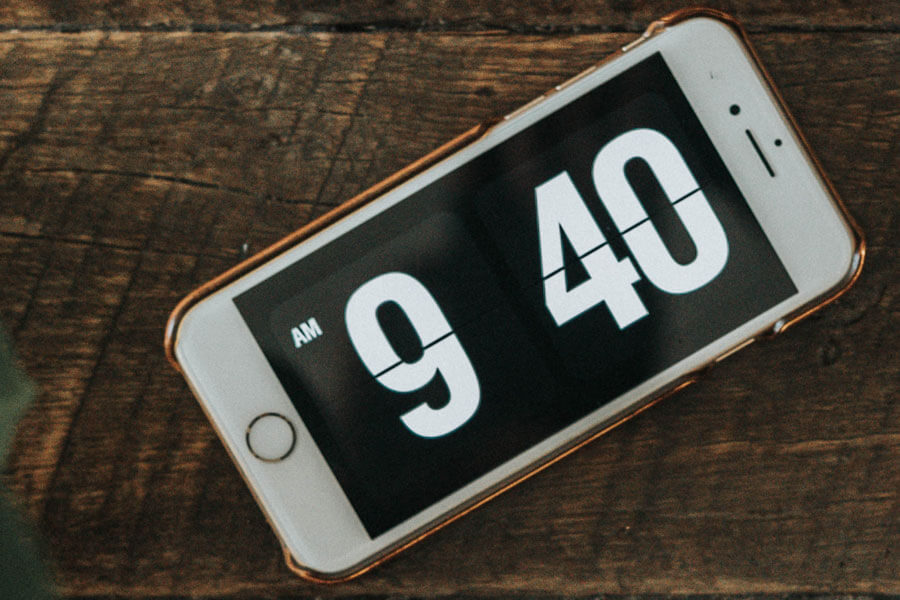 iPhone on a table with a full-screen clock showing 9:40 AM
