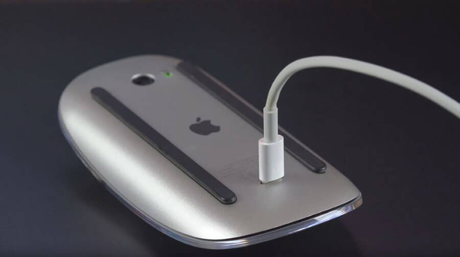 An Apple Magic Mouse 2 on its back while charging (unable to be used)